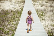 Toddler girl on walkway on beach — Stock Photo