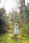 Menina de pé contra a árvore na floresta — Fotografia de Stock