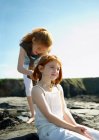 Girl putting shell necklace on sister — Stock Photo