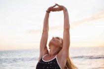 Femme sur la plage bras levés faisant exercice d'étirement — Photo de stock