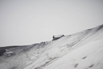 Casa construida en la cima de una colina nevada - foto de stock