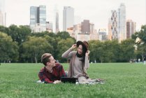Mid adult woman trying on felt hat for boyfriend in Central Park, New York, USA — Stock Photo