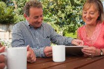 Seniorenpaar schaut sich digitales Tablet im Freien an — Stockfoto