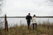 Giovane famiglia che cammina all'aperto, accanto al lago, vista posteriore — Foto stock
