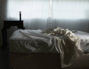 Незроблене ліжко в ранковому світлі — стокове фото