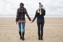Frauen halten Händchen am Strand — Stockfoto