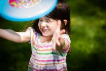 Chica joven lanzando frisbee en el jardín - foto de stock