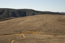 Vista lejana de la corredora corriendo por el paisaje, Thousand Oaks, California, EE.UU. - foto de stock