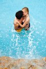 Молода пара цілується в басейні, високий кут — стокове фото