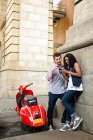 Casal por scooter, olhando para o celular — Fotografia de Stock
