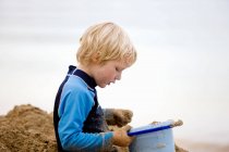 Menino brincando com areia na praia, foco em primeiro plano — Fotografia de Stock