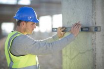 Surveyor using spirit level on construction site pillar — Stock Photo