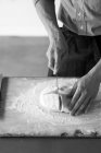 Abgeschnittenes Bild vom Bäcker, der frischen Teig schneidet — Stockfoto