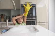 Menina puxando a luva de borracha no lavatório — Fotografia de Stock