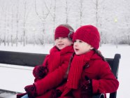 Дівчата сидять на лавці в снігу — стокове фото