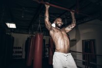 Masculino boxer fazendo pull ups com gritted dentes no ginásio — Fotografia de Stock