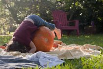 Girl lying on pumpkin in the garden — Stock Photo