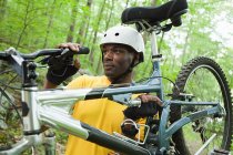 Männlicher Radfahrer trägt Fahrrad im Wald — Stockfoto