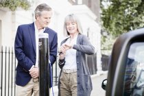 Couple charging electric car on street — Stock Photo