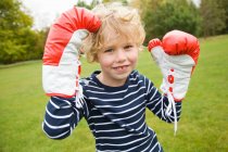 Garçon jouer avec des gants de boxe à l'extérieur — Photo de stock