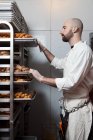 Butcher with racks of sausages on trays — Stock Photo
