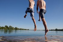 Отец и сын прыгают в озеро — стоковое фото
