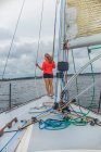 Visão traseira de comprimento total da jovem mulher no arco de veleiro olhando para longe — Fotografia de Stock