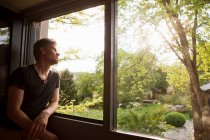 Людина захоплюється пейзажем з вікна — стокове фото