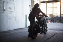 Female mechanic working on motorcycle in workshop — Stock Photo
