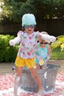 Mädchen und Kleinkind Schwester spielen in Schaumbad im Garten — Stockfoto