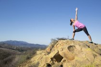 Mujer practicando yoga pose on hill, Thousand Oaks, California, Estados Unidos - foto de stock