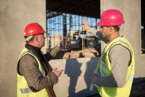Архитектор и строитель обсуждают оконную раму на строительной площадке — стоковое фото