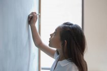 Mädchen schreibt eine Summe auf eine Tafel — Stockfoto