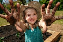 Young girl in garden with muddy hands — Stock Photo