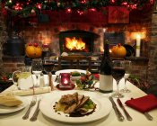 Table servie près de la cheminée pour le dîner de Noël — Photo de stock