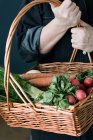 Cropped image of person with basket of vegetables — Stock Photo