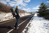 Junge männliche Wanderer wandern auf Landstraße in verschneiter Landschaft, an Land, oregon, usa — Stockfoto
