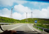Wind turbines and road through car windscreen — Stock Photo