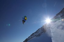 Männlicher Skifahrer springt gegen strahlend blauen Himmel — Stockfoto