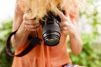 Tiro cortado de mulher com cabelo vermelho fotografando para baixo com SLR digital — Fotografia de Stock