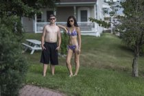 Portrait of teen couple in front of house wearing bathing suits — Stock Photo
