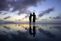 Vista posteriore dei bambini in piedi sulla spiaggia al tramonto — Foto stock