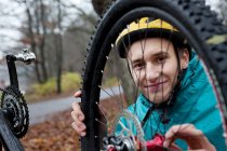 Young man fixing bicycle wheel in forest — Stock Photo