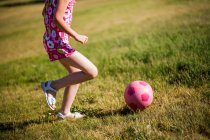 Девушка играет в футбол в поле — стоковое фото