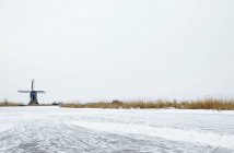 Mulino a vento vicino al lago ghiacciato — Foto stock