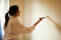 Woman painting room with paintbrush — Stock Photo