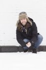 Joven agachado cubierto de nieve calle haciendo bola de nieve - foto de stock
