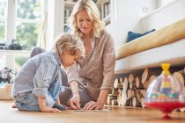 Mother and son sitting on floor, doing puzzle together — Stock Photo