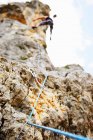 Low angle view of man Climbing cliff at daytime — Stock Photo
