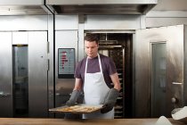 Chef macho horneando galletas en cocina comercial - foto de stock